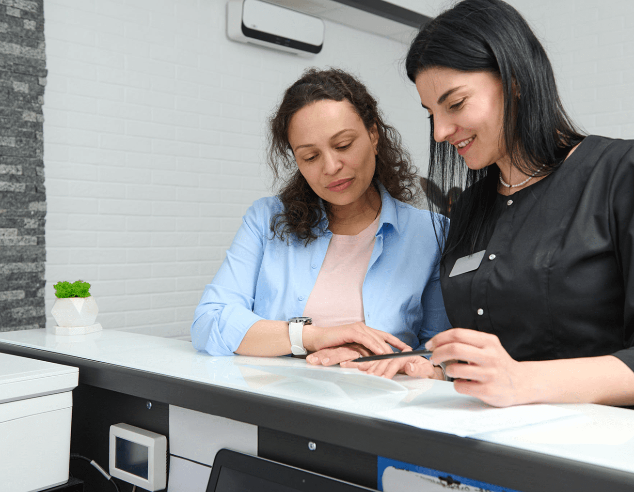 Receptionist assisting a woman at desk